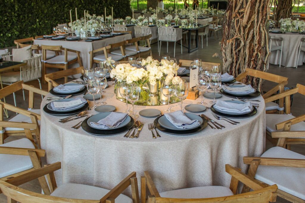 Mesa elegante para banquete de boda o evento formal organizada por Ambrosía Mesa elegantemente montada para un banquete en evento especial, con vajilla fina, copas de cristal y decoración floral.